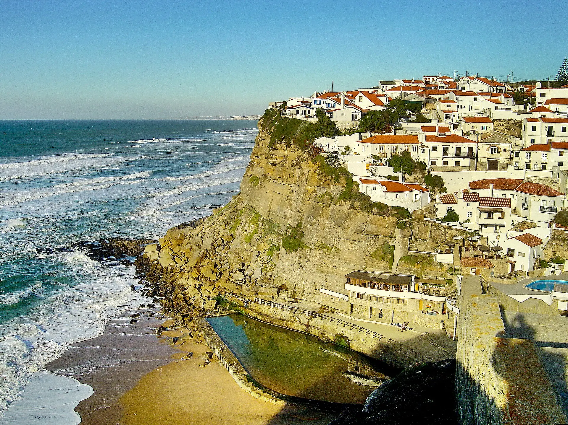 Azenhas do Mar on its cliff, with the natural pool and the beach below